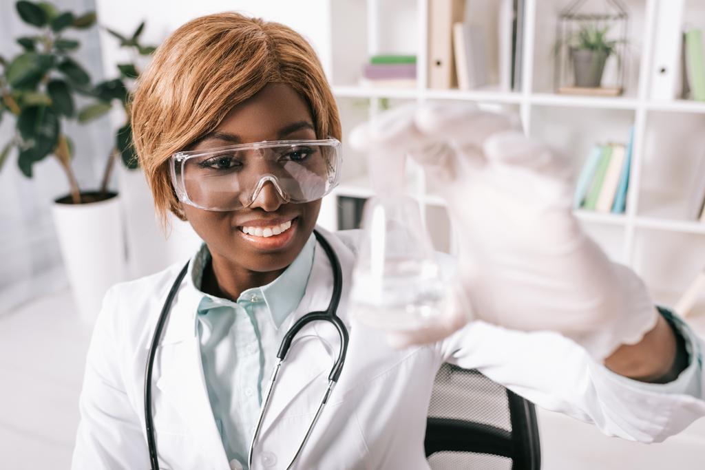 液で試験管を見て美しいアフリカ系アメリカ人の科学者  - 写真・画像