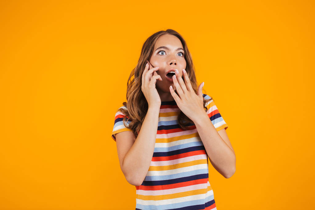 Image d'une jeune fille choquée posant sur fond de mur jaune parlant par téléphone
. - Photo, image