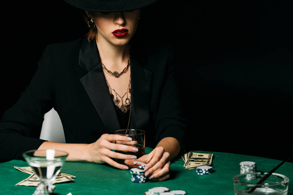 menina atraente em casaco e chapéu segurando copo de uísque e tomando chip de poker no cassino
 - Foto, Imagem