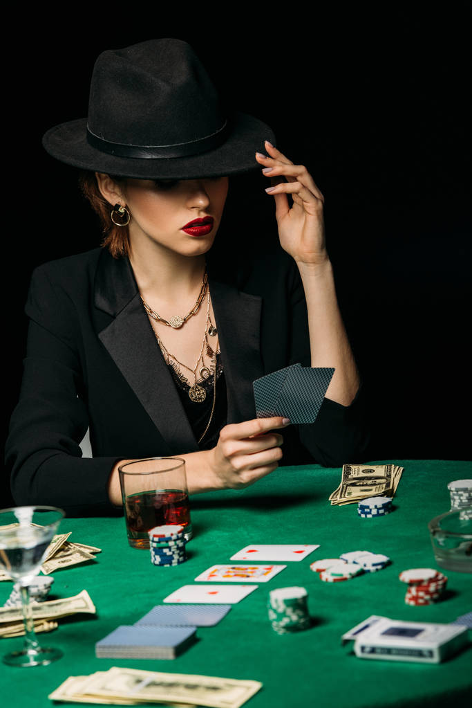 aantrekkelijk meisje in jas en hoed pokeren en bedrijf kaarten in casino - Foto, afbeelding
