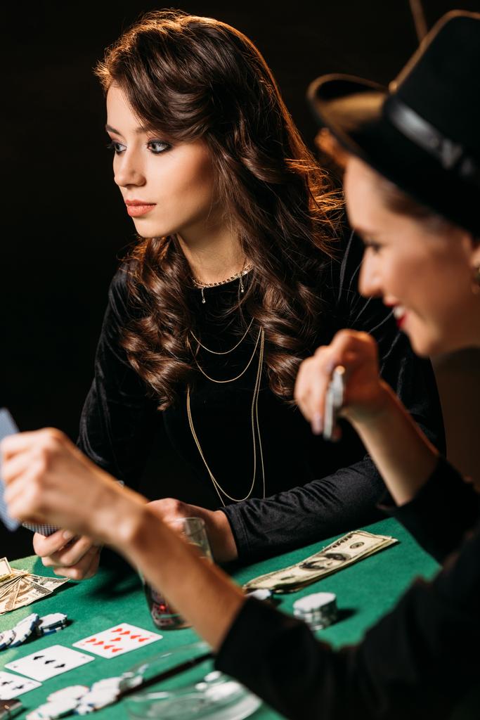 mooie vrouwen spelen van poker met kaarten en chips aan tafel in casino - Foto, afbeelding