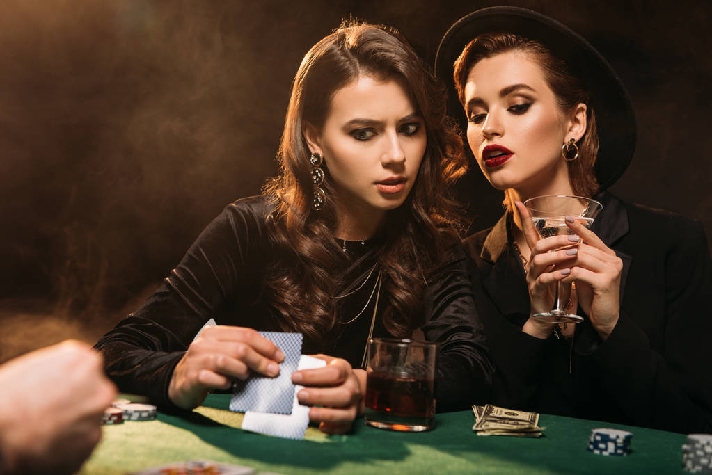 serious attractive girls playing poker at table in casino - Photo, Image