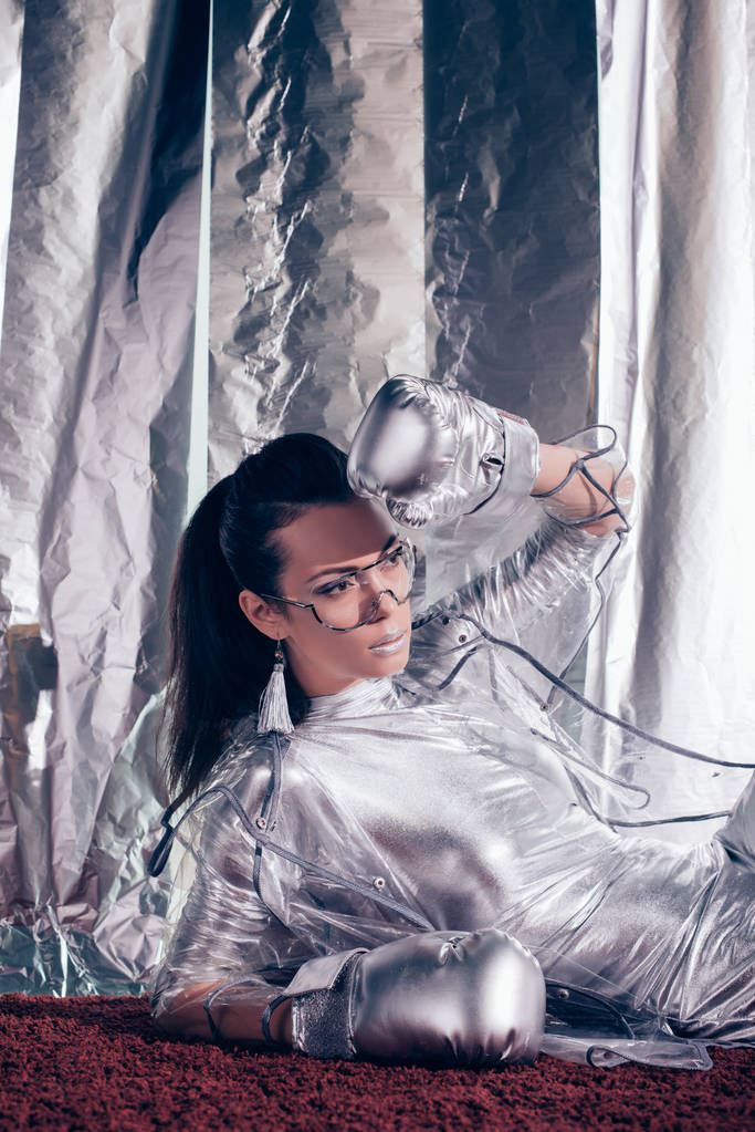 hermosa chica elegante posando en traje de cuerpo, impermeable y guantes de caja de plata sobre fondo metálico
 - Foto, imagen