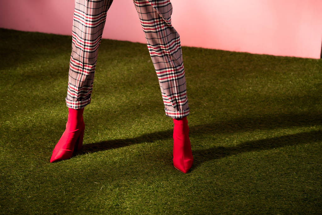 vista parcial del modelo posando en pantalones a cuadros de moda en alfombra verde
 - Foto, Imagen