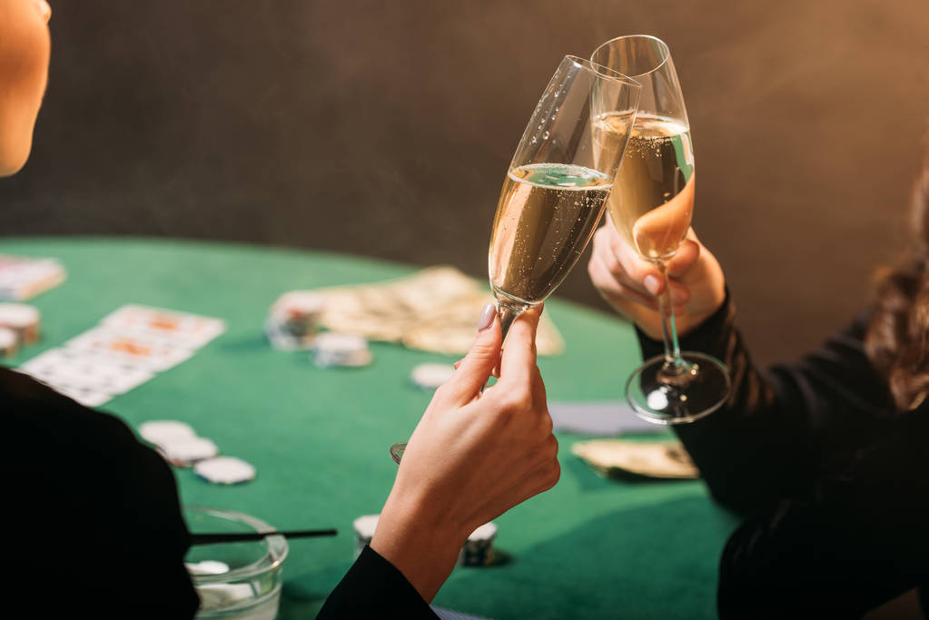 カジノのポーカー テーブルでシャンパンのグラスをチリンと女の子の画像をトリミング - 写真・画像