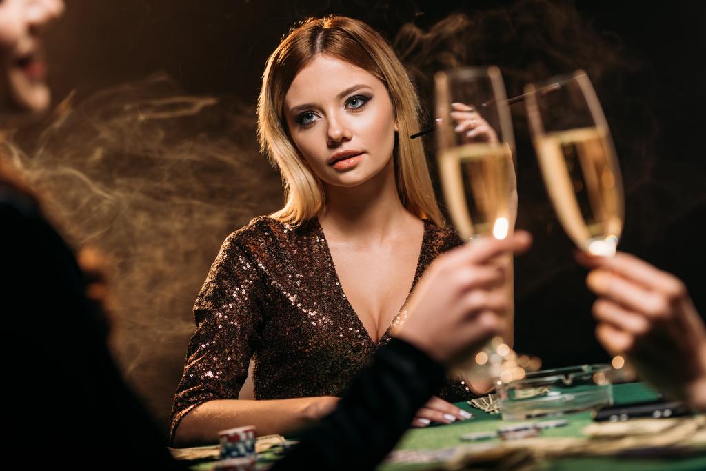 meisjes rammelende met glazen champagne aan pokertafel in casino - Foto, afbeelding