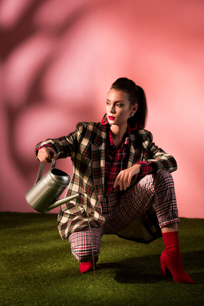 beautiful woman in fashionable checkered suit posing with watering can - Photo, Image