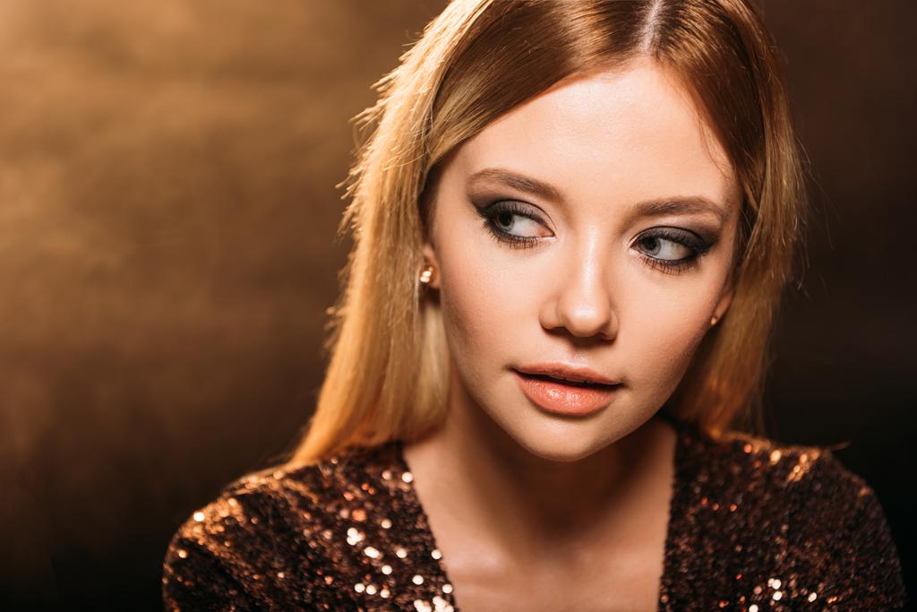 portrait of attractive girl with makeup in sparkling party dress looking away on brown - Photo, Image