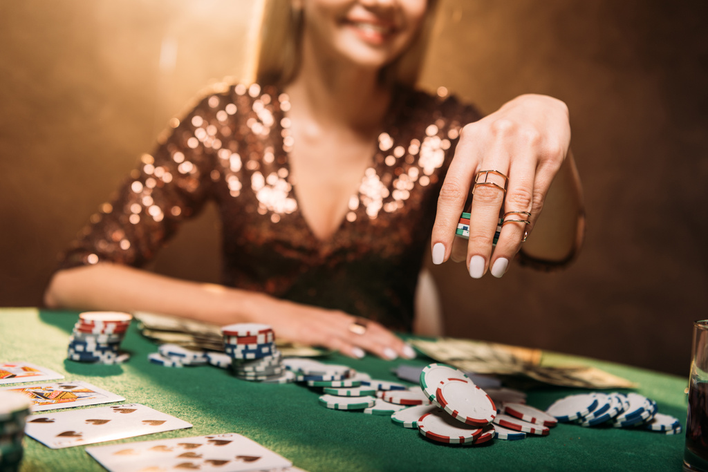 abgeschnittenes Bild eines lächelnden Mädchens beim Pokerspielen am Tisch im Casino - Foto, Bild