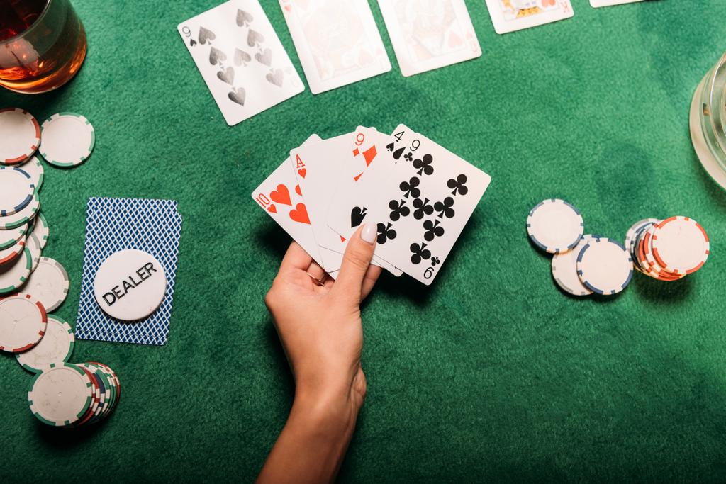 imagem cortada de menina jogando poker à mesa no casino e segurando cartas - Foto, Imagem