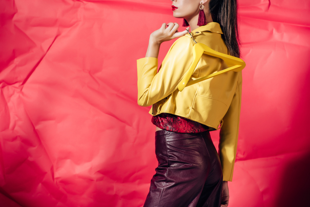 sarı deri ceket askı üzerinde kırmızı arka plan ile poz kız görünümünü kırpılmış - Fotoğraf, Görsel