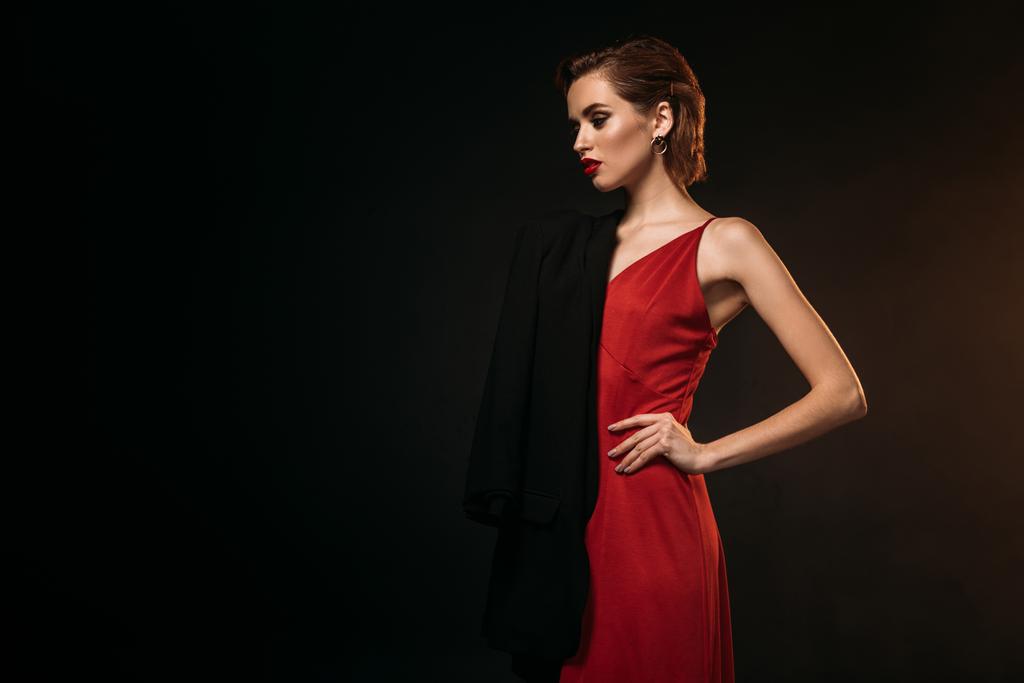 chica atractiva en vestido rojo y chaqueta negra de pie aislado en negro
 - Foto, imagen