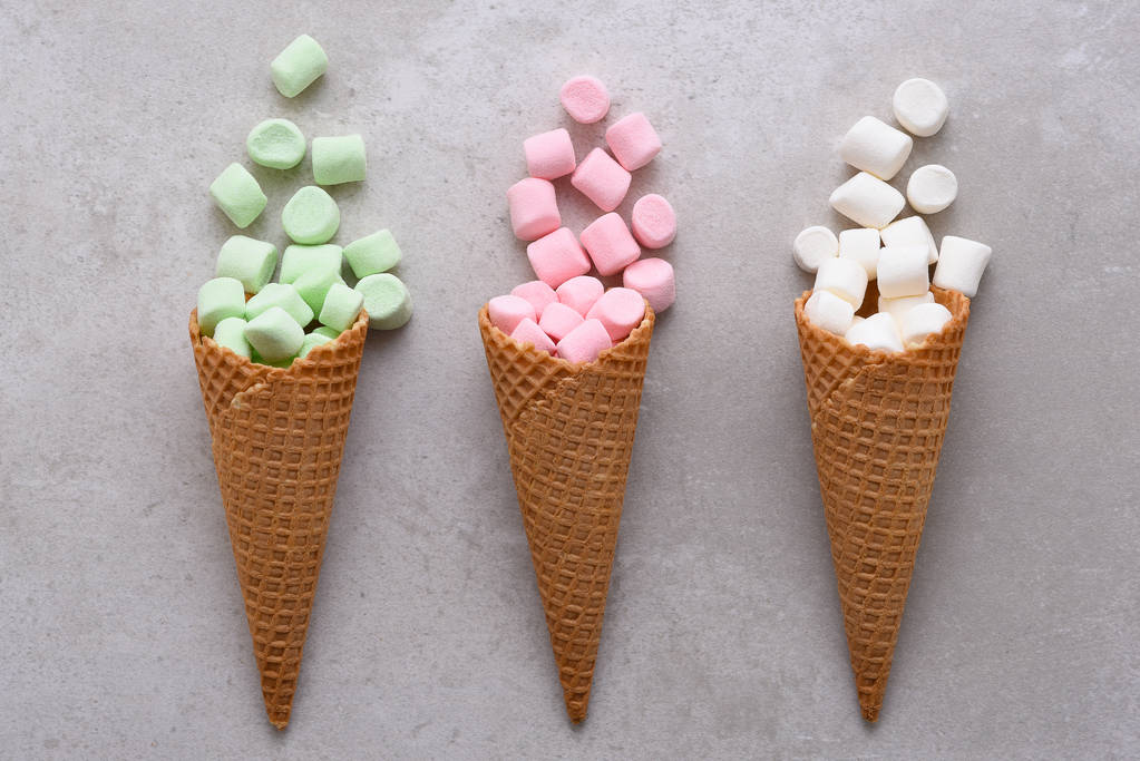 Closeup tří cukru Vaflové kornouty na zmrzlinu plněné barevné marshmallows vysypal na stůl vedle sebe.  - Fotografie, Obrázek