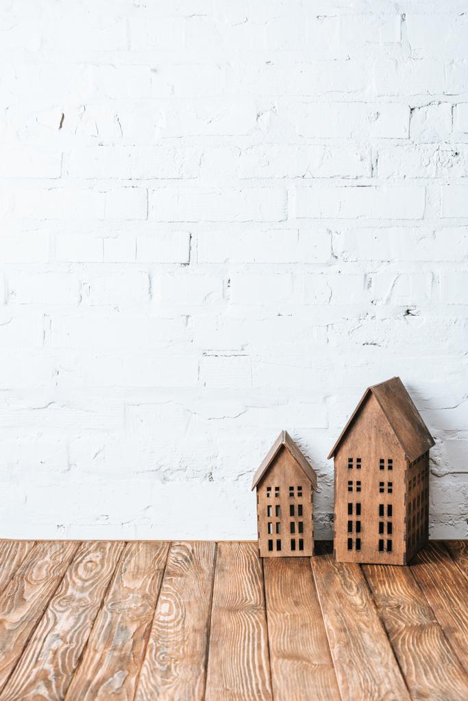 Rustiek huis modellen op houten tafel in de buurt van witte bakstenen muur - Foto, afbeelding