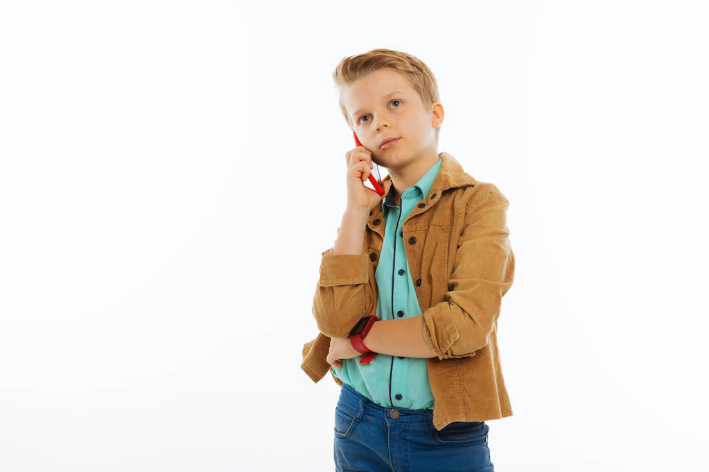 Приятный симпатичный мальчик делает телефонный звонок.
 - Фото, изображение