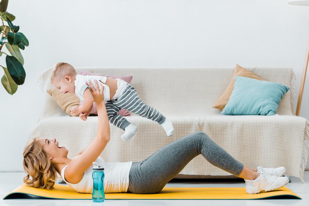 atraktivní žena ležící na fitness mat a hrál se synem - Fotografie, Obrázek