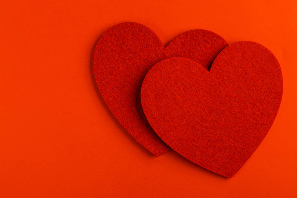 Parlak kırmızı zemin üzerine iki kırmızı keçe kalp. St. Valentine's day. Kopya alanı - Fotoğraf, Görsel