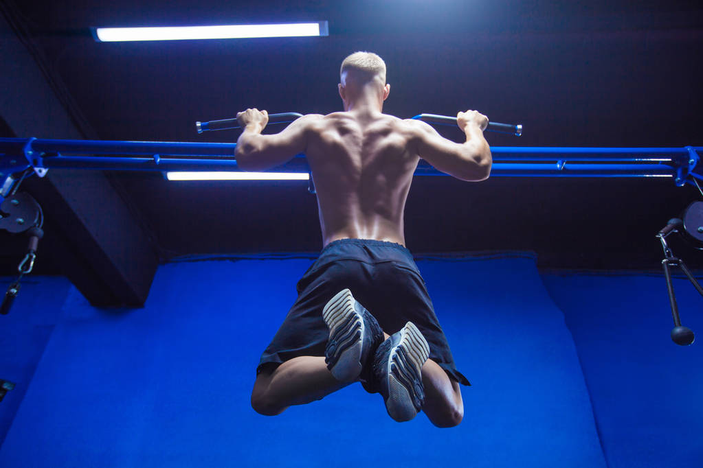 Fitness homme faisant pull-ups dans une salle de gym pour une séance d'entraînement dos vue arrière
 - Photo, image