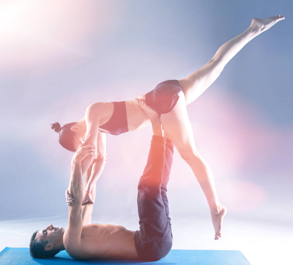 Mladý pár společně cvičí acro jógy na mat ve studiu. Acroyoga. Několik jóga. Partner jóga. - Fotografie, Obrázek