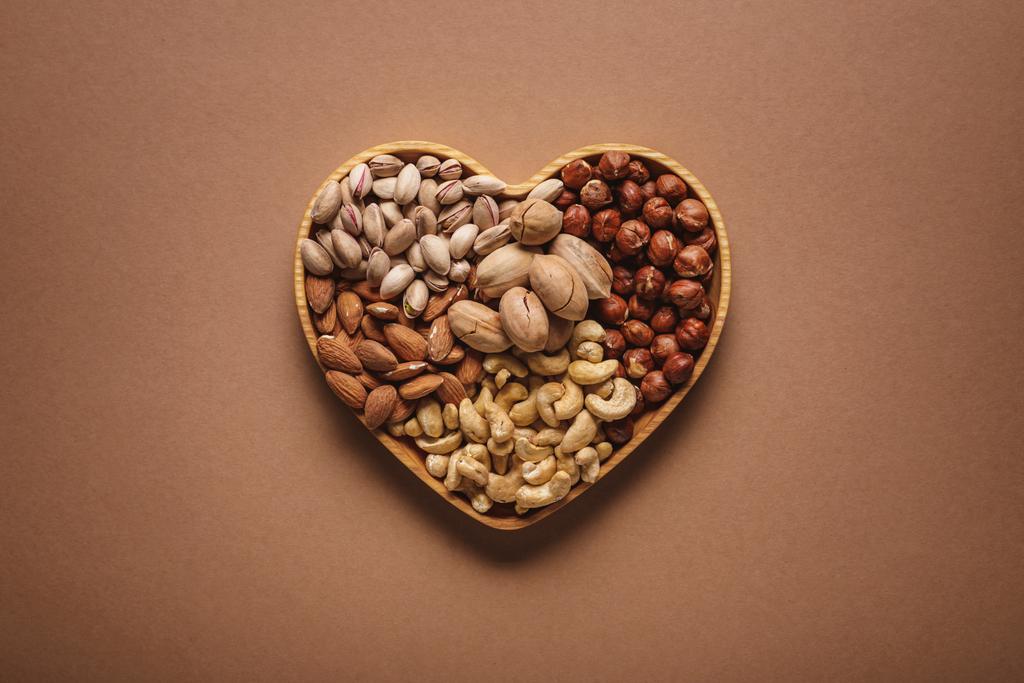 вид зверху на асортимент різних горіхів у формі серця на коричневому тлі
 - Фото, зображення