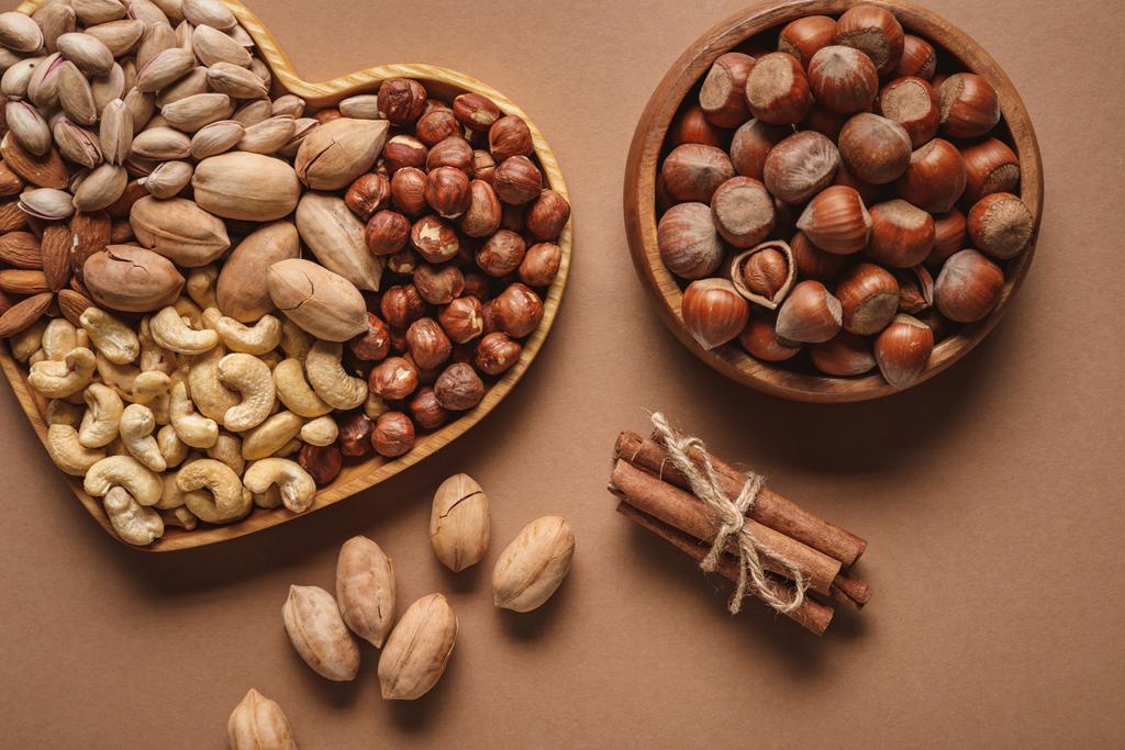 flat lay with variety of nuts in bowls arranged on brown background - Photo, Image
