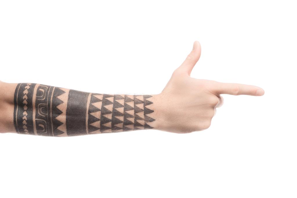 обрізаний вид татуйованого чоловіка, що вказує праворуч пальцем ізольовано на білому
 - Фото, зображення
