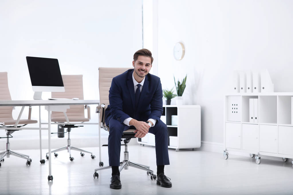 Joven hombre de negocios sentado en silla de oficina en el lugar de trabajo
 - Foto, imagen