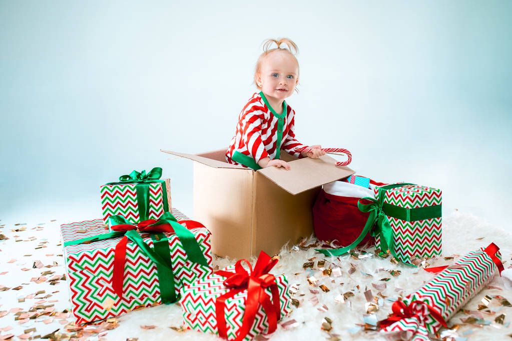 Menina bonito 1 ano de idade sentado na caixa sobre fundo de Natal. Temporada de férias
. - Foto, Imagem