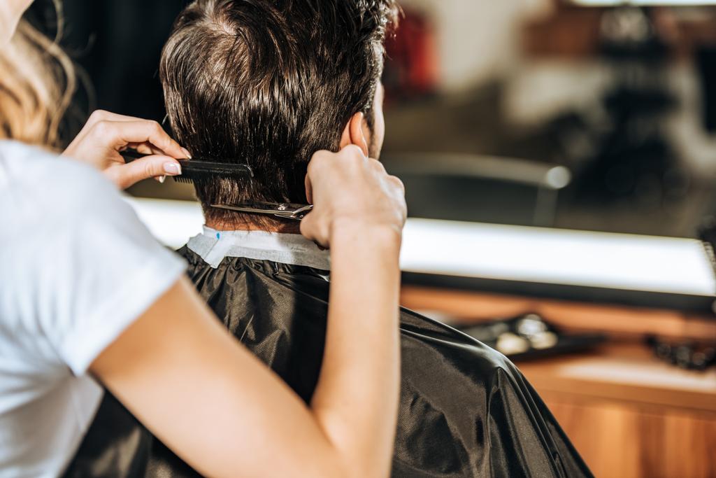 abgeschnittene Aufnahme eines Friseurs, der männlichen Kunden im Schönheitssalon die Haare schneidet - Foto, Bild