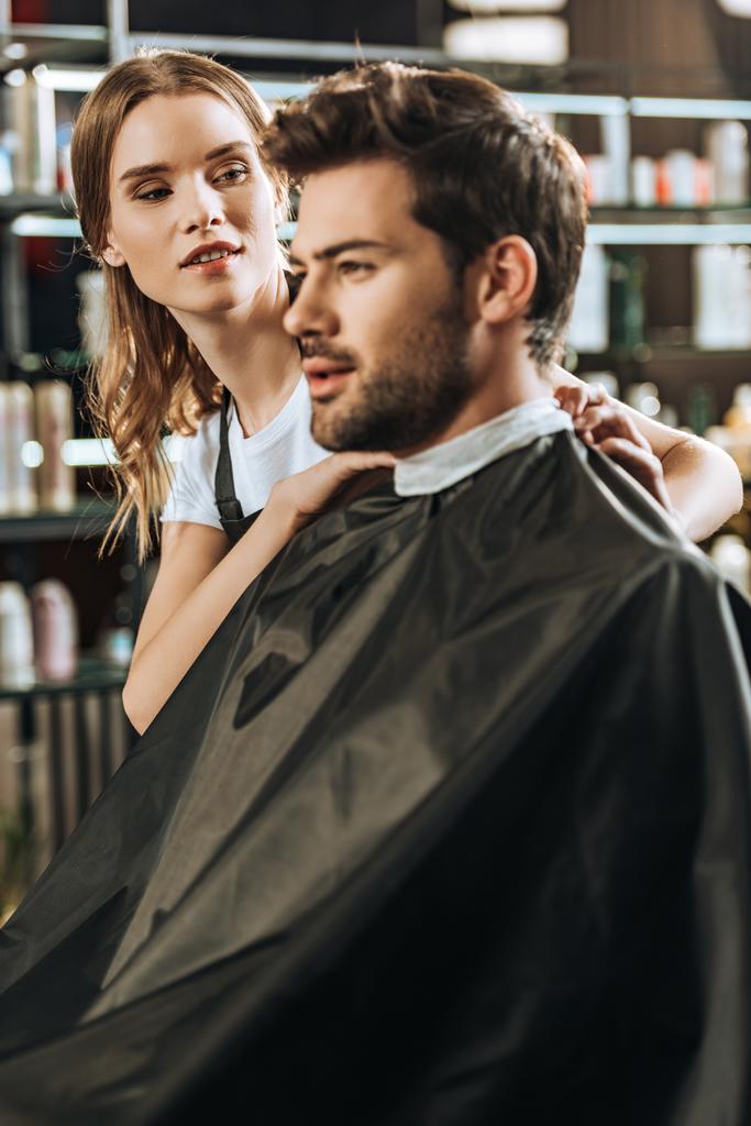 jeune coiffeuse regardant bel homme dans le salon de beauté
  - Photo, image