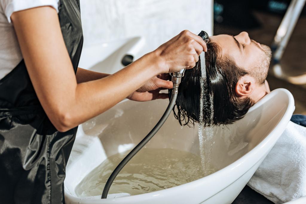 vue partielle de coiffeur laver les cheveux à beau jeune client masculin dans le salon de beauté
  - Photo, image