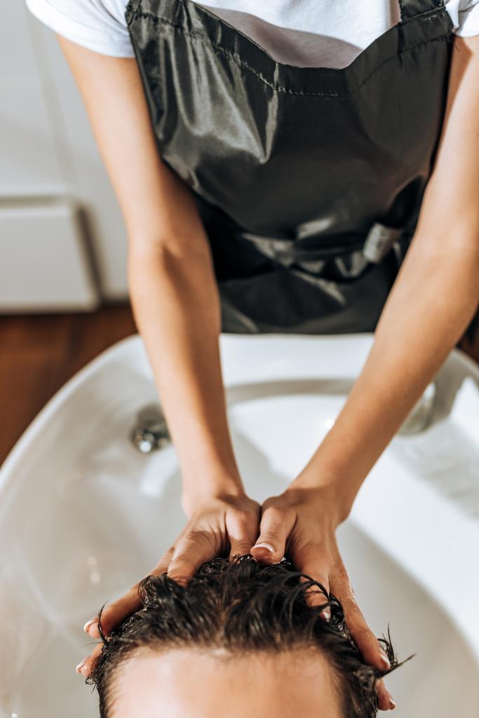vue partielle de coiffeur laver les cheveux à l'homme dans le salon de beauté
 - Photo, image