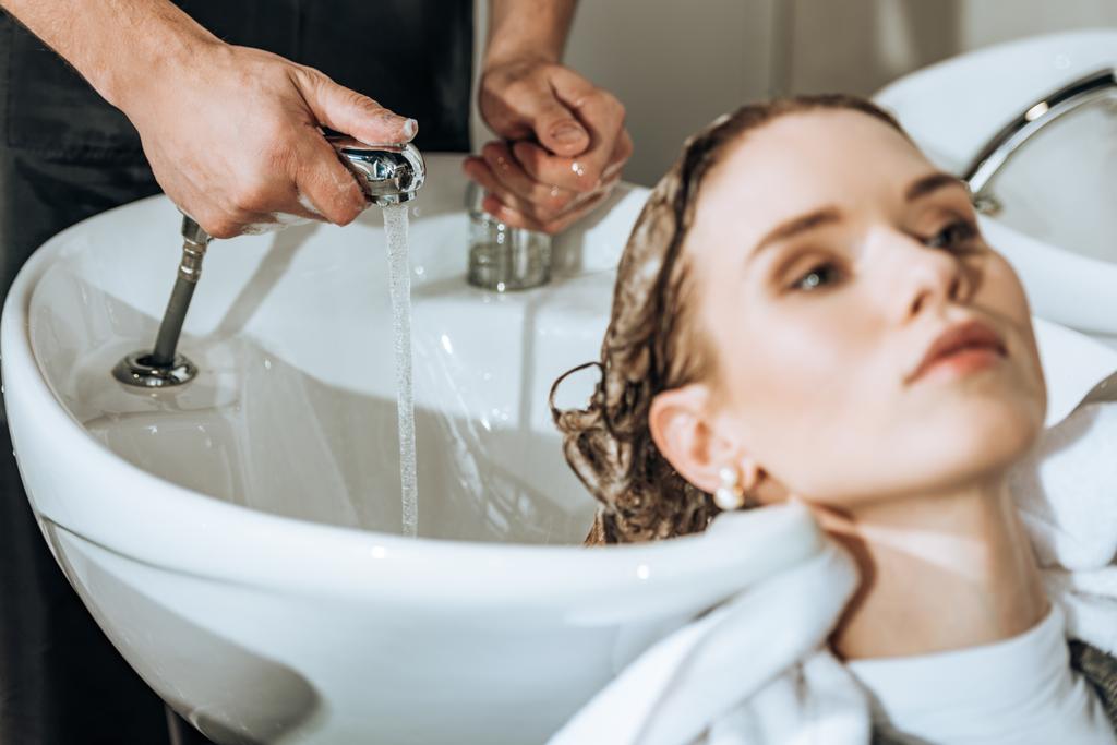 水のチェックや、ビューティー サロンで若い女性に髪を洗う美容師のショットをトリミング - 写真・画像