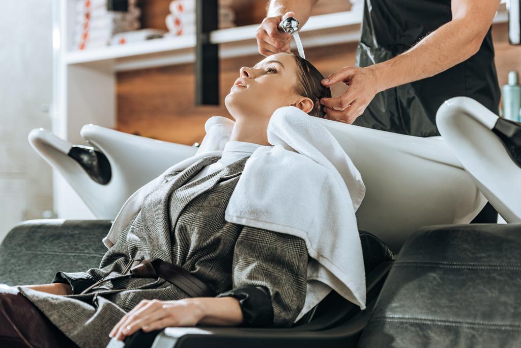 plan recadré de coiffeur laver les cheveux à la jeune femme attrayante dans le salon de beauté
  - Photo, image