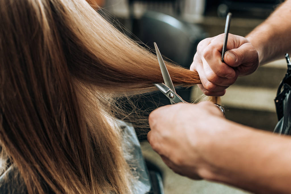 Colpo ritagliato di parrucchiere che fa il taglio di capelli a giovane donna nel salone di bellezza  - Foto, immagini