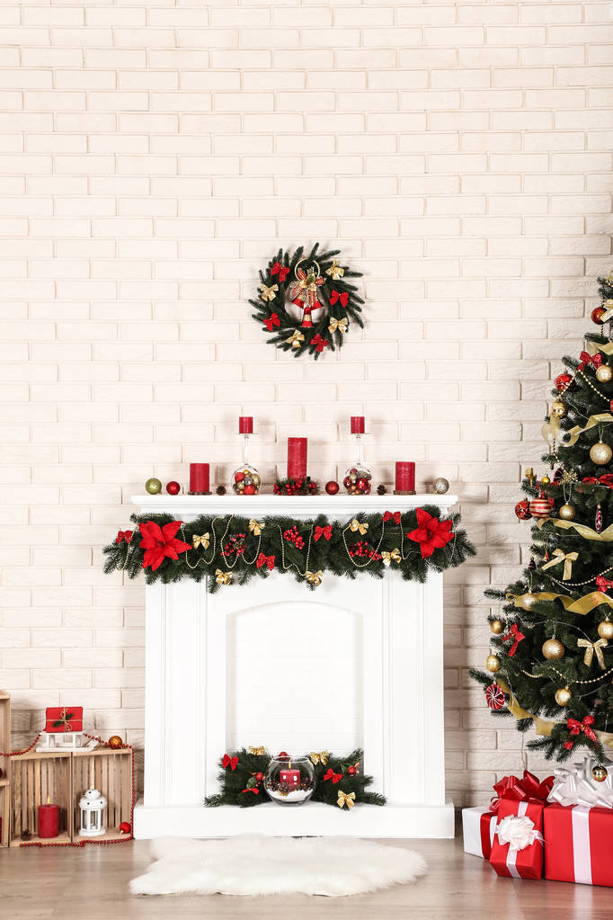 Chimenea blanca decorada cerca del árbol de Navidad en el fondo de la pared de ladrillo
 - Foto, imagen