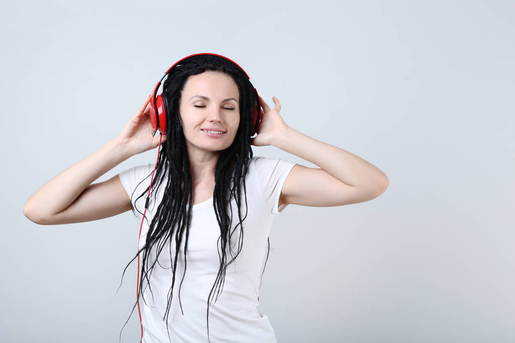 Cute young woman with headphones on grey background - Photo, Image