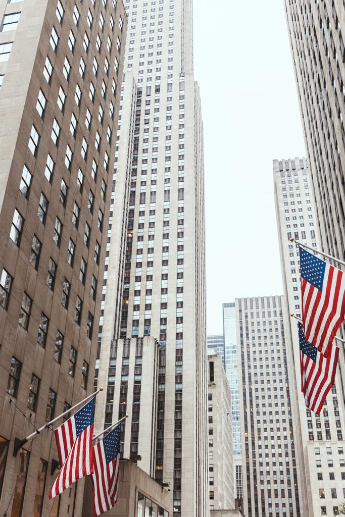 low angle view of skyscrapers and american flags on new york city street, usa - Photo, Image