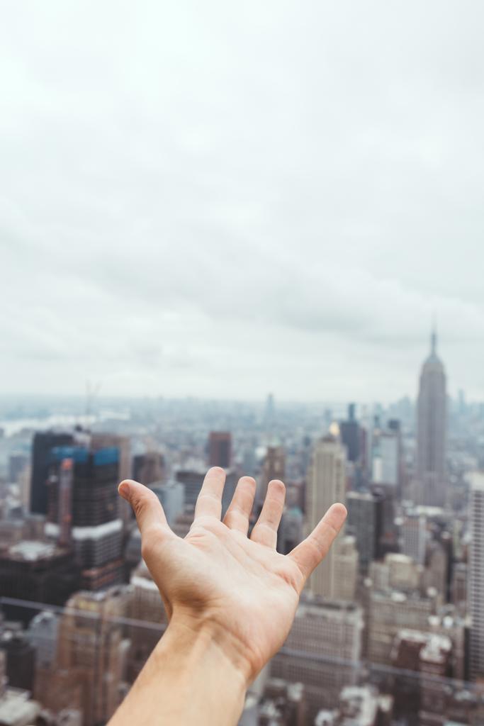 vista parcial de la mano masculina y borrosa vista de la ciudad de Nueva York en el fondo
 - Foto, imagen
