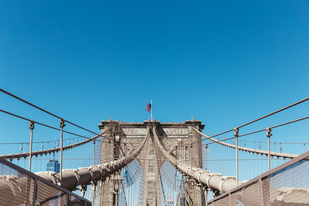 Бруклінський міст з американським прапором на чистому блакитному фоні неба, Нью-Йорк, США
 - Фото, зображення
