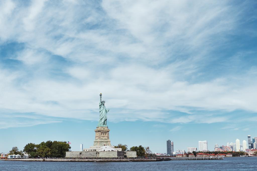 青い曇り空の背景でアメリカ ニューヨークの自由の女神のリバティー、ニューヨーク、アメリカ合衆国 - 2018 年 10 月 8 日: 像 - 写真・画像