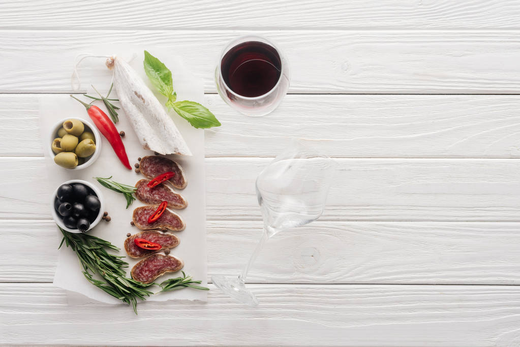skład żywności przy lampce czerwonego wina oraz różne mięsa przekąski na biały blat drewniany - Zdjęcie, obraz