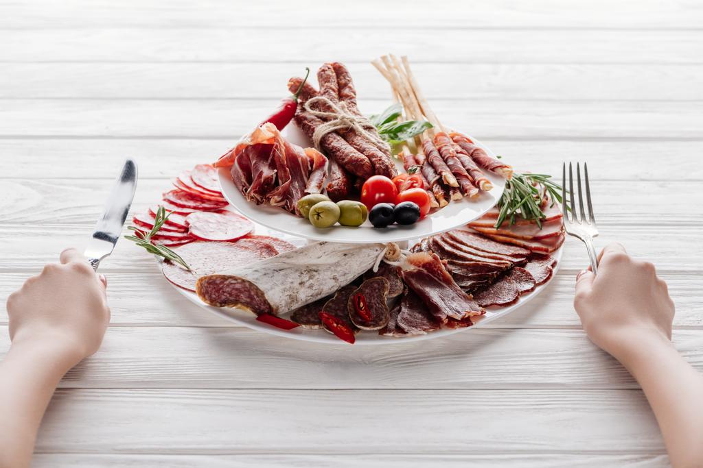 cropped shot of woman with cutlery at white wooden surface with different meat appetizers - Photo, Image