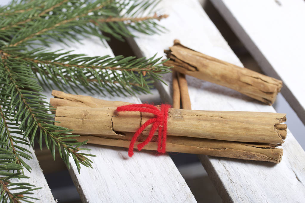 Cinnamon sticks next to the fir branches. On a wooden box. - Photo, Image