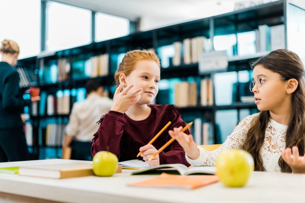 чарівні школярки розмовляють під час навчання разом у бібліотеці
 - Фото, зображення