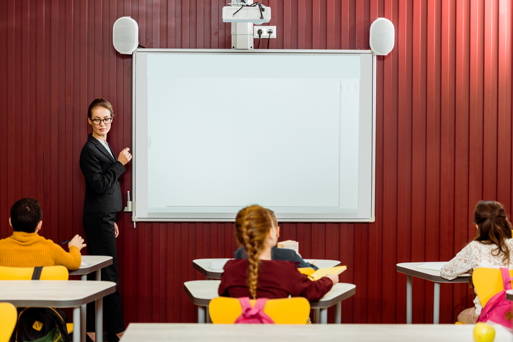 arkadan okul masaları ve öğretmen yapım tanıtımı beyaz tahta oturan görünüşü  - Fotoğraf, Görsel