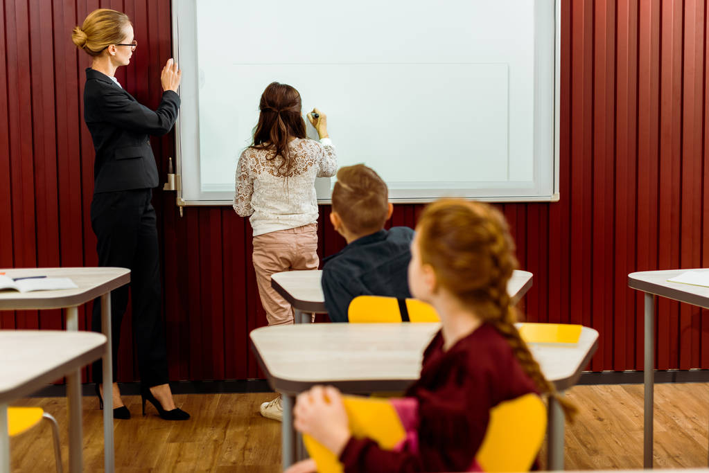 schoolkinderen en leraar studeren met interactieve whiteboard achter   - Foto, afbeelding