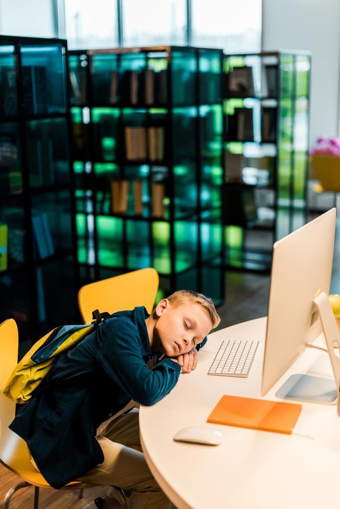 wysoki kąt widzenia uczniak z plecaka spanie na biurko z komputera w bibliotece - Zdjęcie, obraz