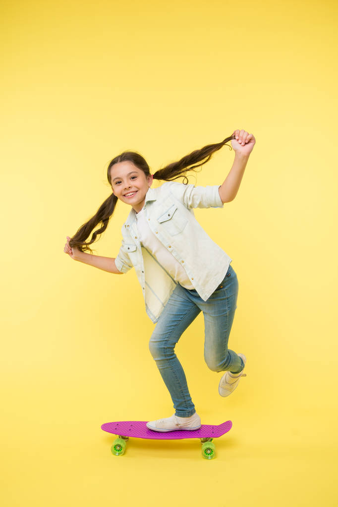 Hobby favoriete activiteit. Kind glimlachende gezicht staan op skateboard. Penny board leuke kleurrijke skateboard voor meisjes. Laten we gaan. Meisje rijden penny board gele achtergrond. Kind heeft plezier met penny board - Foto, afbeelding