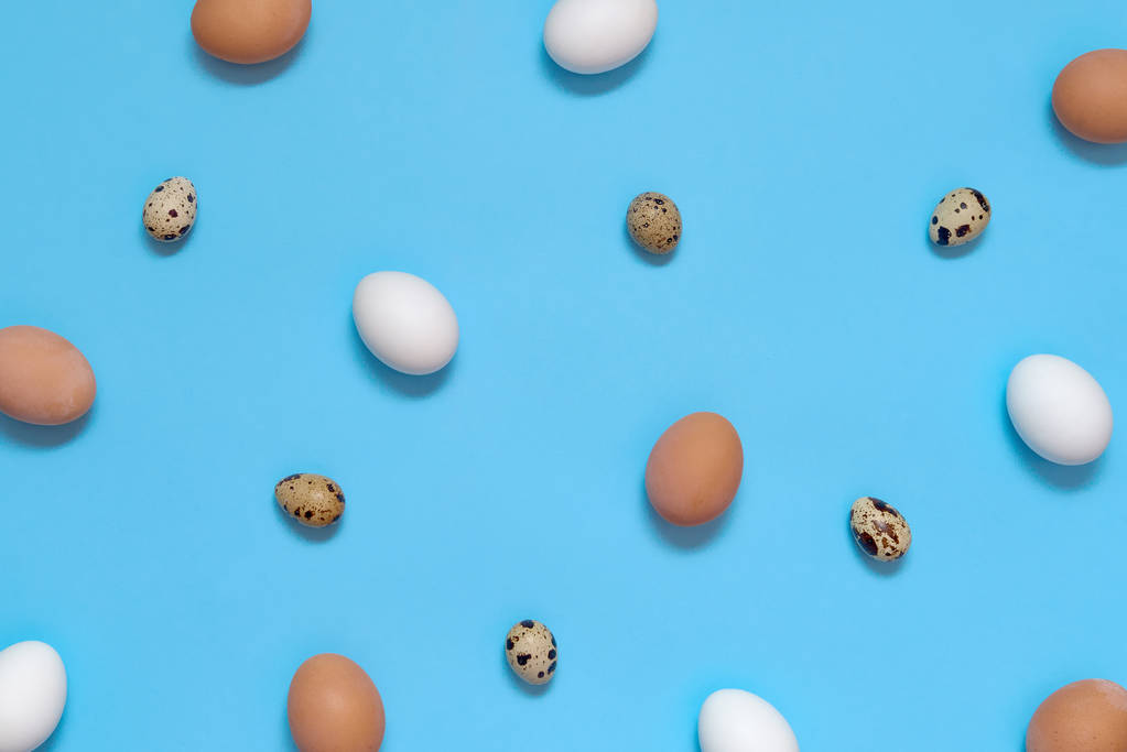 Куриные белые и коричневые яйца и перепелиные яйца на голубом фоне, скопировать пространство. Концепция здорового питания. Вид сверху, плоский. Пасхальные яйца. Happy Easter
 - Фото, изображение